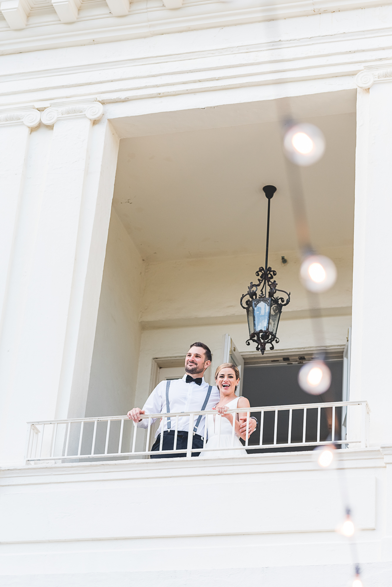 Wedding at The Wadsworth Mansion at Long Hill in Middletown CT. Bride and groom standing on a balcony looking down to their guests.