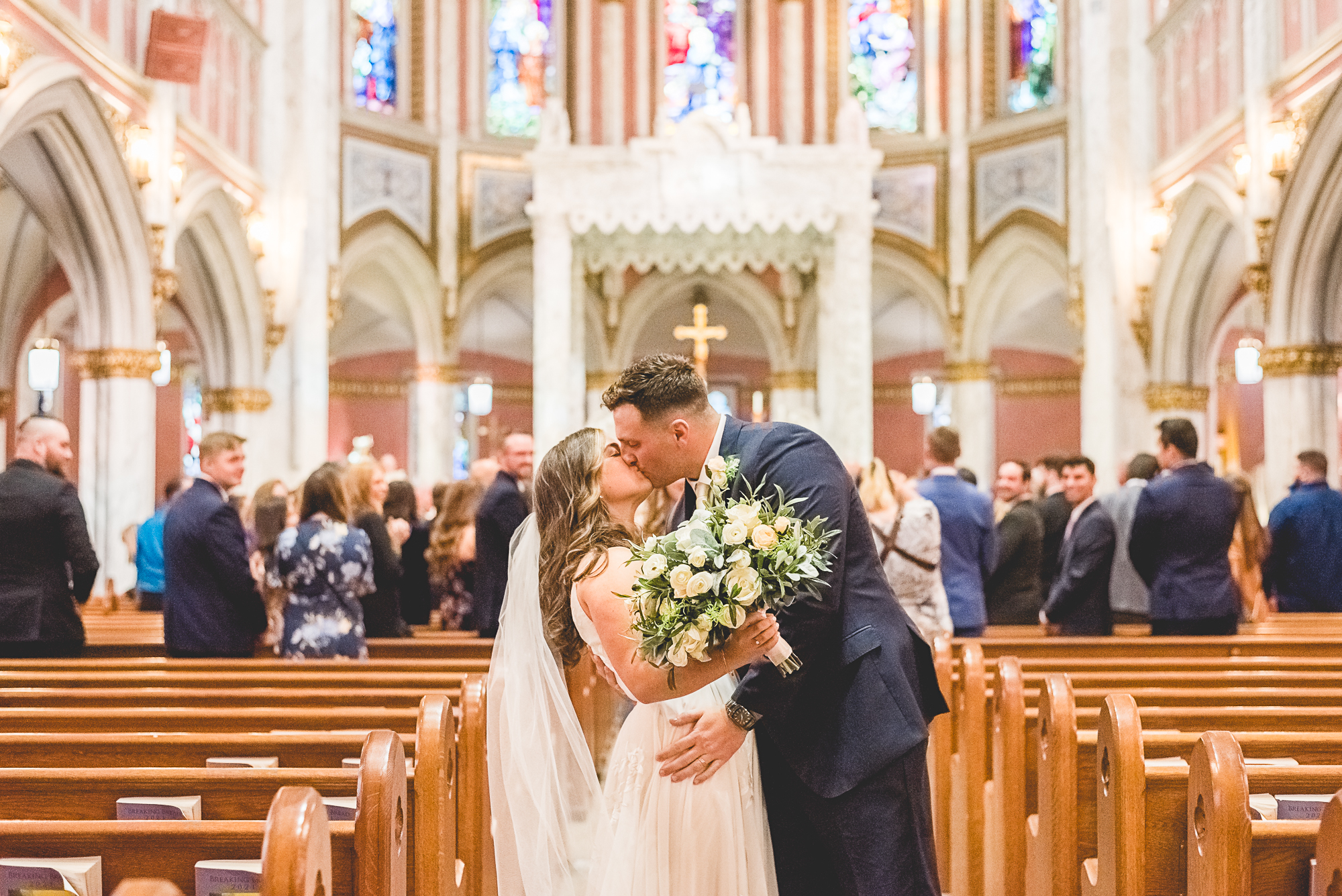 Wedding ceremony in a church in Bristol RI. Bride and groom kissing at the end of the aisle after the ceremony.