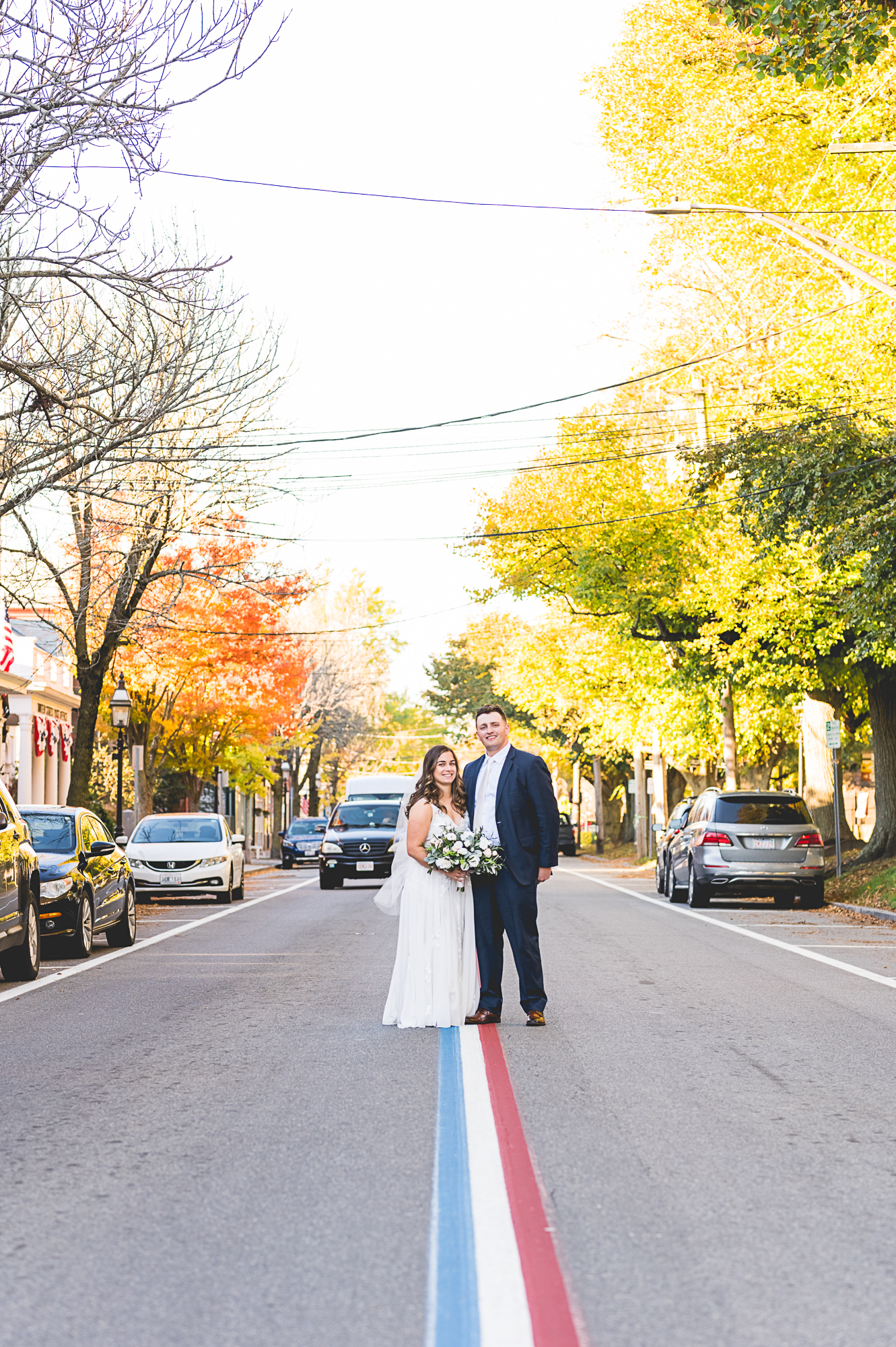 Wedding in Bristol RI. Bride and groom standing on Fourth of July parade route lines.