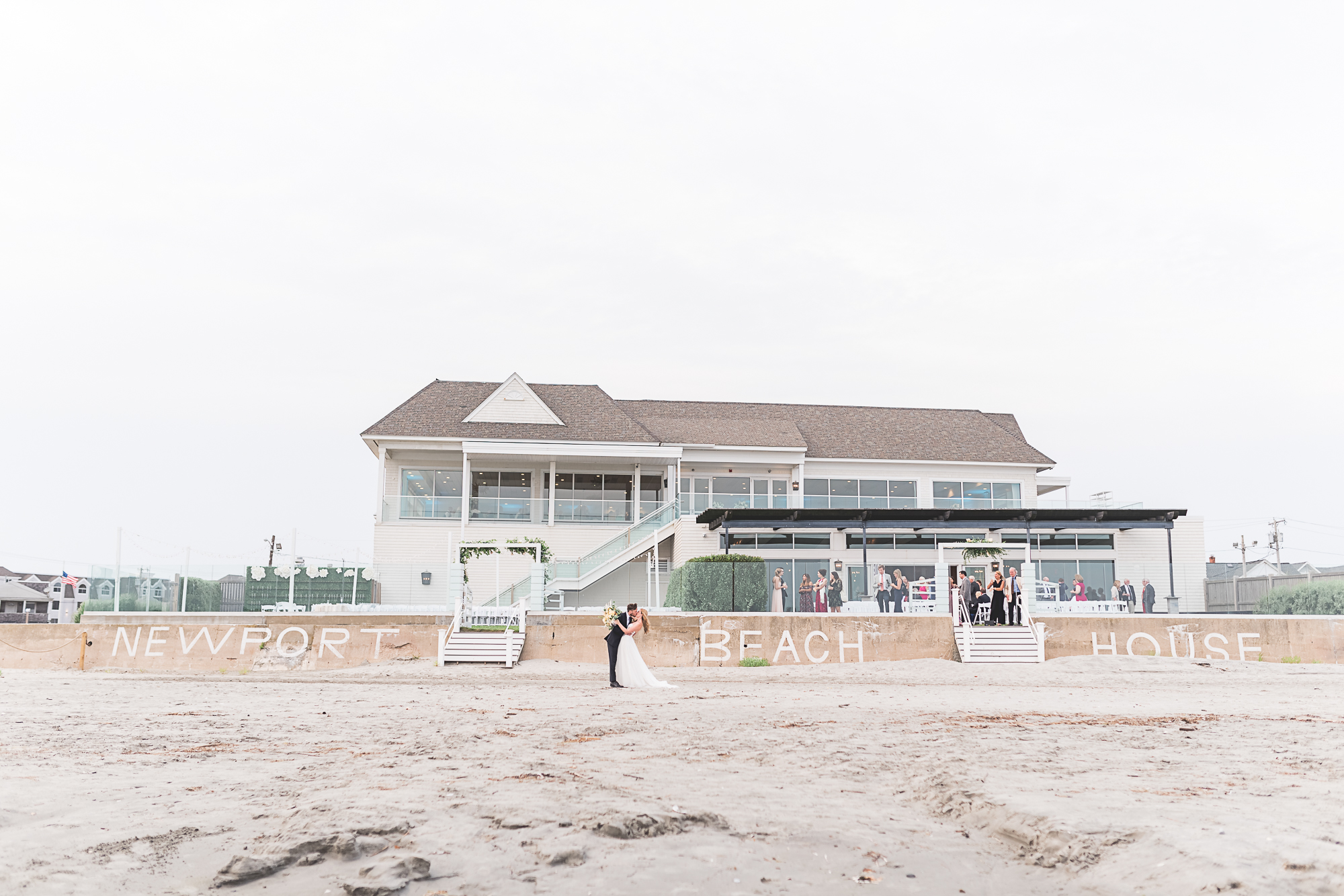 The beach side view of Newport Beach House: a Longwood Venue in Newport, RI. Bride and groom dancing on the beach.